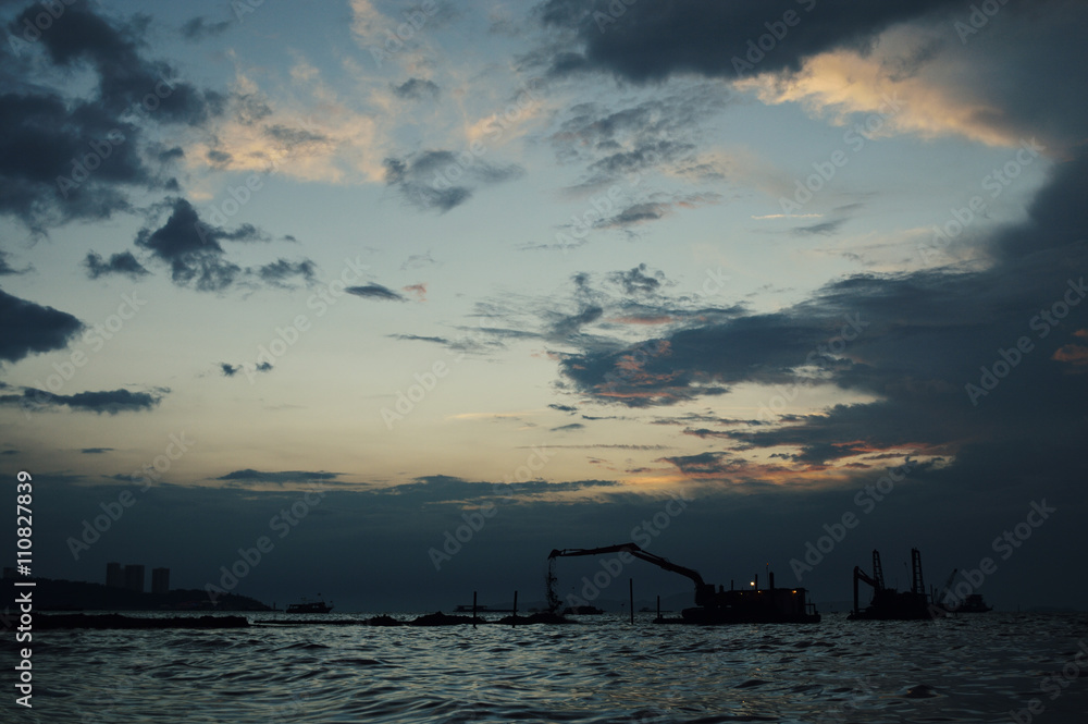 Silhouettes of construction crane at sunset in sea, Pattaya Thai
