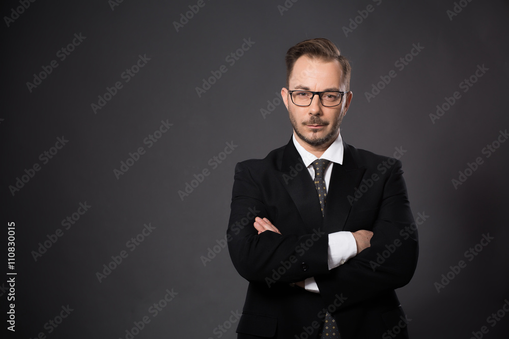 Portrait of serious businessman posing with his arms crossed or folded in studio. Handsome bearded man in glasses looking at camera. Portrait of serious businessman posing with his arms crossed or folded in studio. Handsome bearded man in glasses looking at camera.