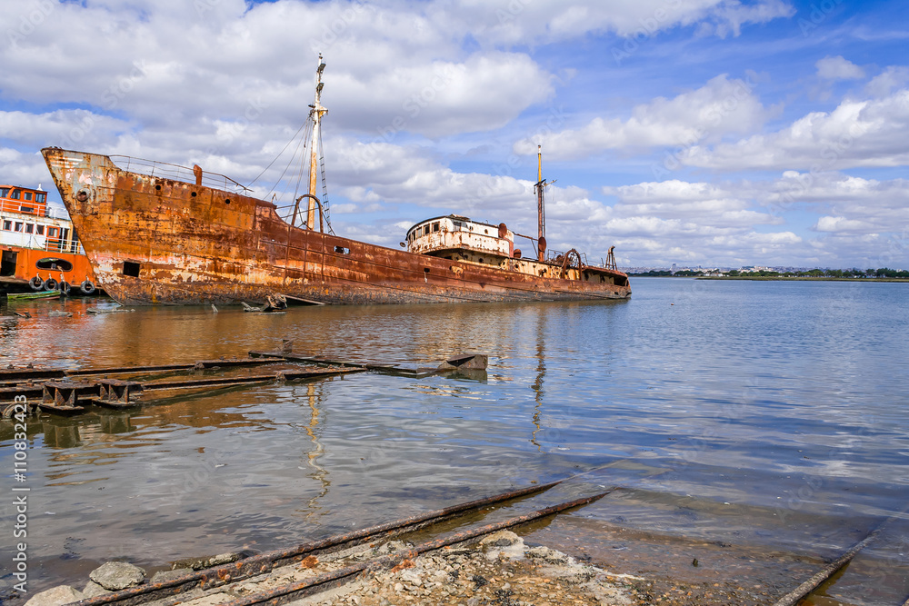 Old ship run aground and rusting in the shore. Seixal, Portugal.