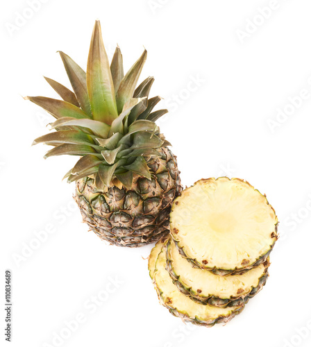Whole pineapple with stack of slices isolated over white background