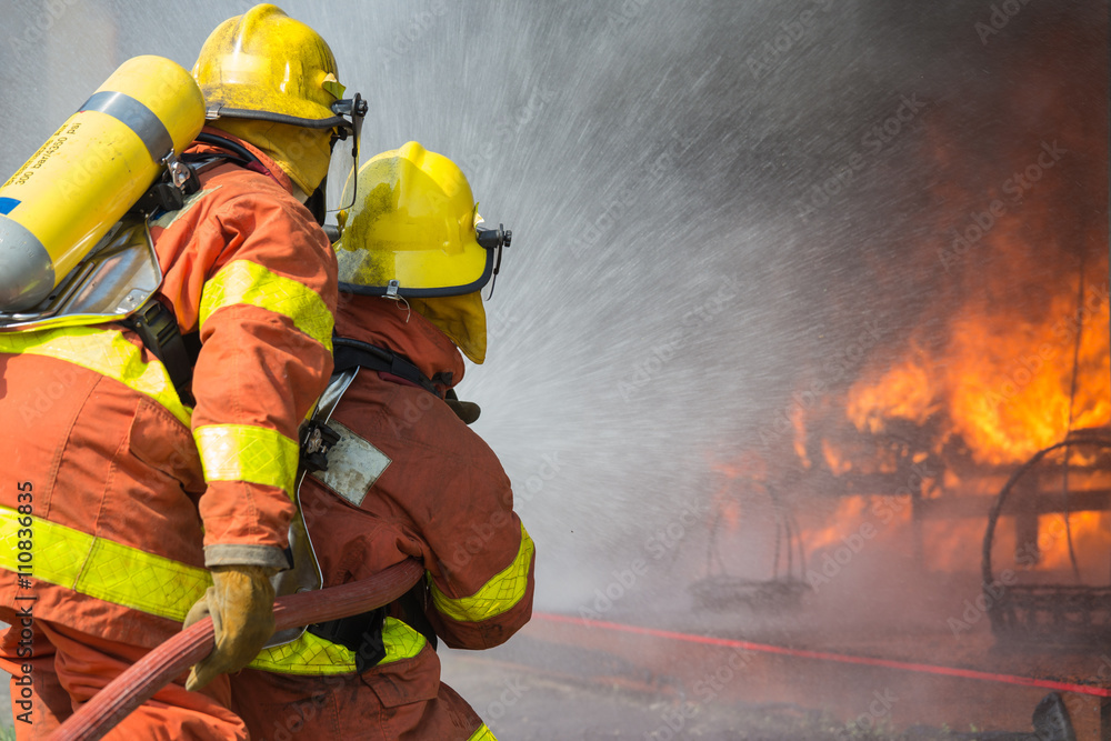 Obraz premium 2 firefighters spraying water in fire fighting operation