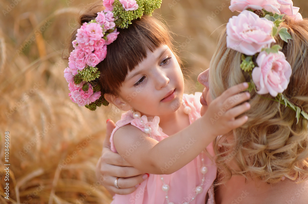 The daughter and mother look at each other, the daughter straightens the wreath of roses on her head The daughter and mother look at each other, the daughter straightens the wreath of roses on her head