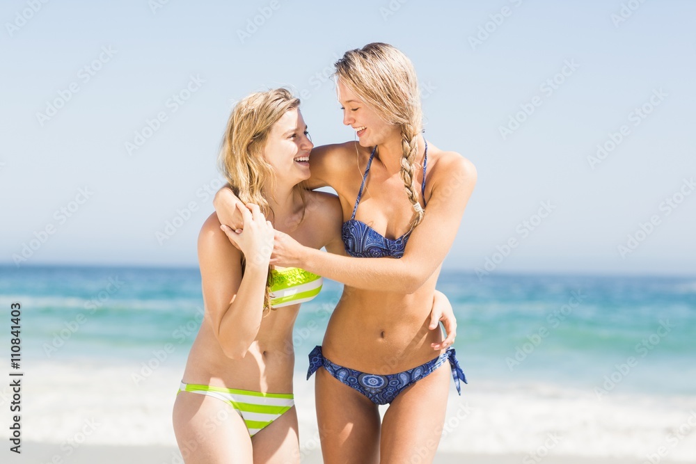 Two happy women embracing on the beach