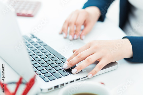 The female hands on the keyboard of her laptop computer