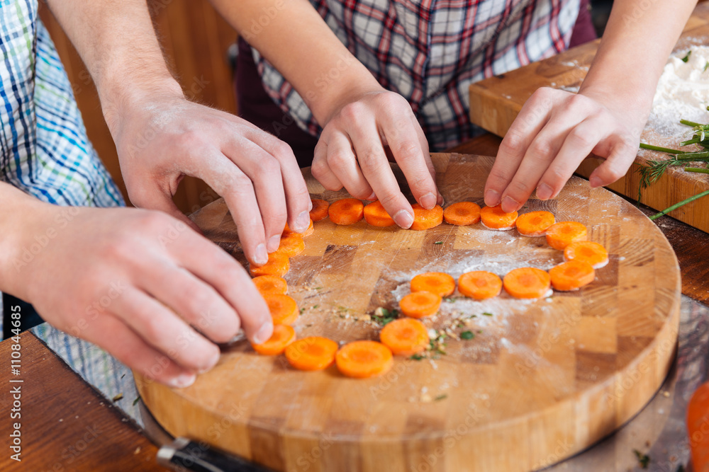 Couple making heart with cutted carrots on the kitchen Couple making heart with cutted carrots on the kitchen