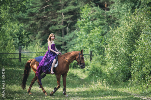 girl in a beautiful purple dress sitting on a horse
