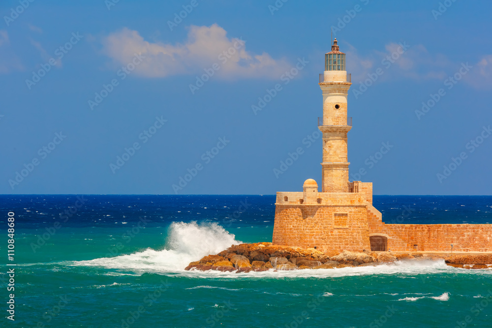 Waves beat against the lighthouse in old harbour of Chania in the summer sunny day, Crete, Greece