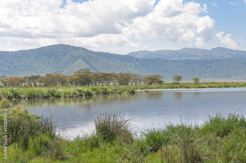 View on huge Ngorongoro caldera (extinct volcano crater) from within with large lake before against blue sky background. Great Rift Valley, Tanzania, East Africa. 