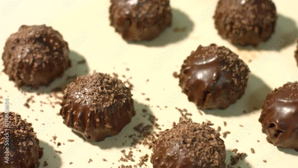 Dark candies on light background. Sweets laying on beige cloth. Custom made candies on table. Tasty dessert with chocolate filling. Dark candies on light background. Sweets laying on beige cloth. Custom made candies on table. Tasty dessert with chocolate filling.