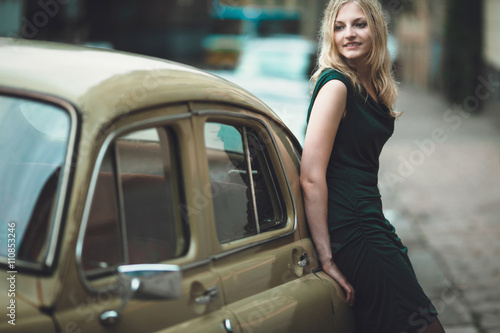 interesting girl standing near old car and looks to the camera