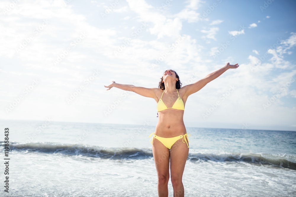 Carefree woman in bikini standing on the beach Carefree woman in bikini standing on the beach