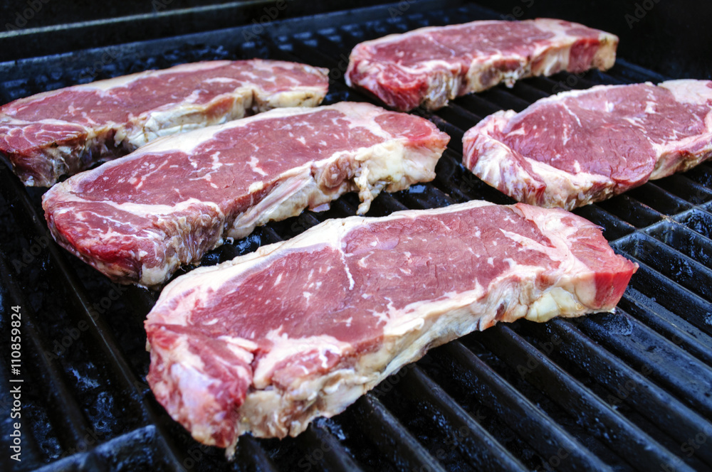 Five Juicy Steaks Cooking On The Grill