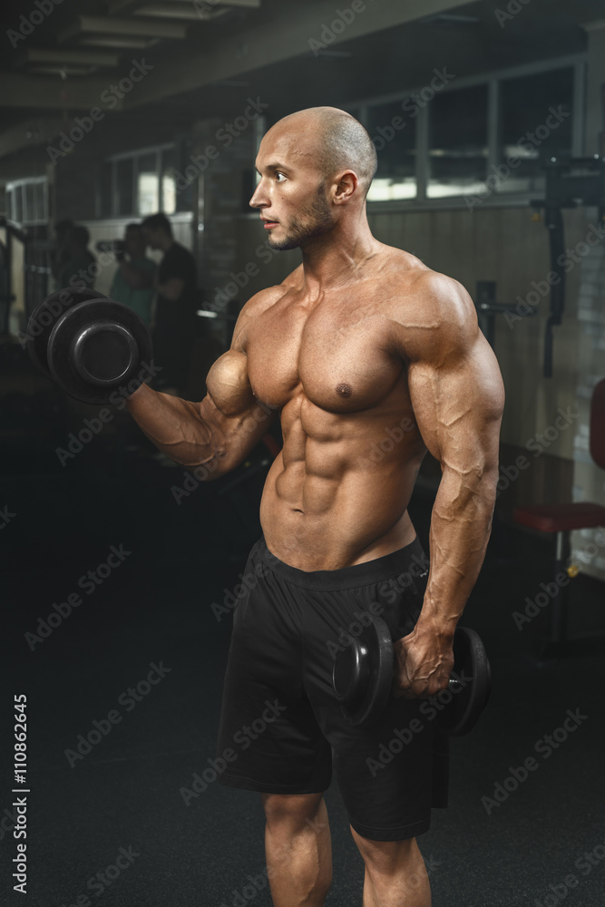 very powerfull athletic guy working in gym with dumbbells very powerfull athletic guy working in gym with dumbbells