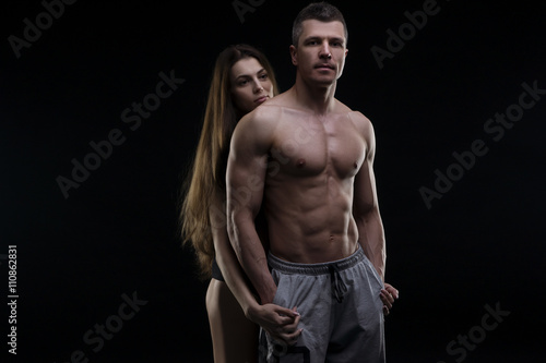 Young adult muscular man and woman. Sexy couple on black background © staras