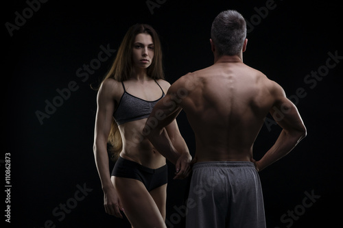 Young adult muscular man and woman. Sexy couple on black background