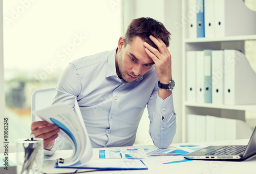 stressed businessman with papers at office