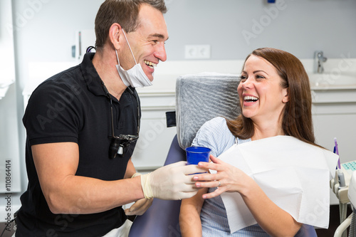 Dentist handing cup of water to a patient after treatment