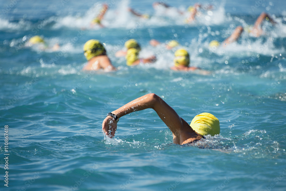 Triathlon swimmers inthe open sea,view from behind