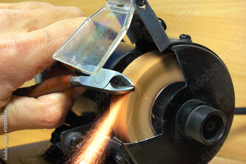 Sharpening side cutting pliers on electrical grinding wheel photo