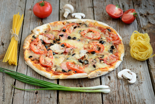 Tasty pizza and vegetables on a wooden table