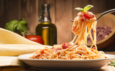 spaghetti with amatriciana sauce in the dish on the wooden table