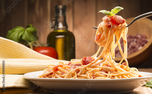 Fototapeta spaghetti z sosem amatriciana w naczyniu na drewnianym stole
