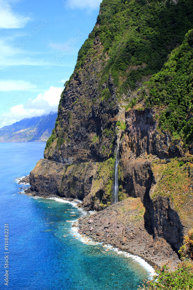 Beautiful coast of Madeira Island in the Atlantic Ocean, Portugal. Dark blue sea, reefs and waterfall.