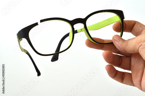 Hand holding broken eyeglasses, mistake in a hand