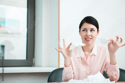 business woman sitting her desk getting rid of old papers with pleasure.