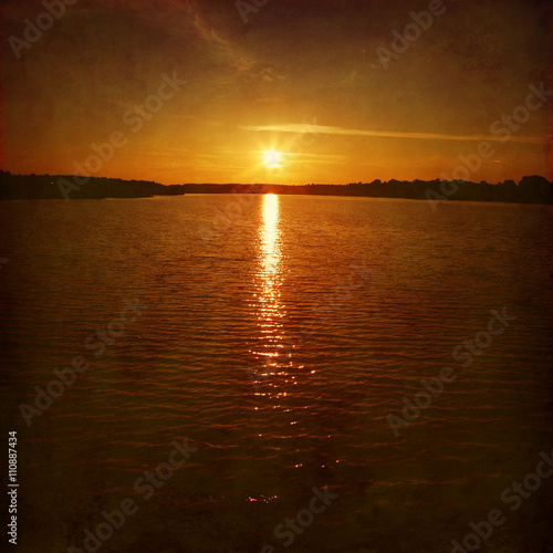 Sunset over water surface. Grunge style. © Elena Volkova