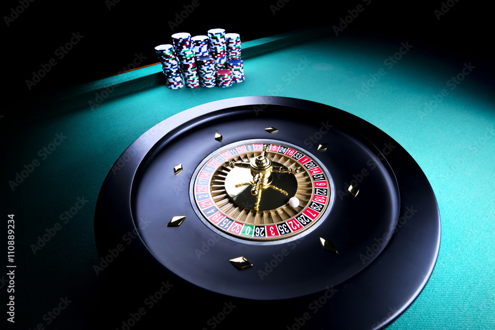 casino theme, high contrast image of casino roulette and playing chips on green canvas casino theme, high contrast image of casino roulette and playing chips on green canvas