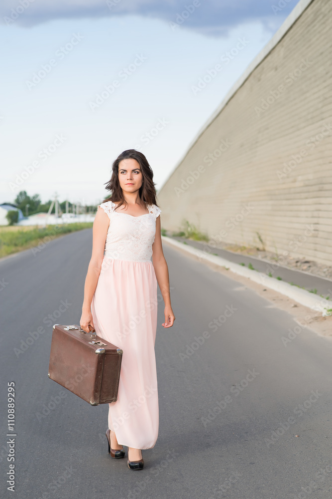 young woman with a suitcase on the road