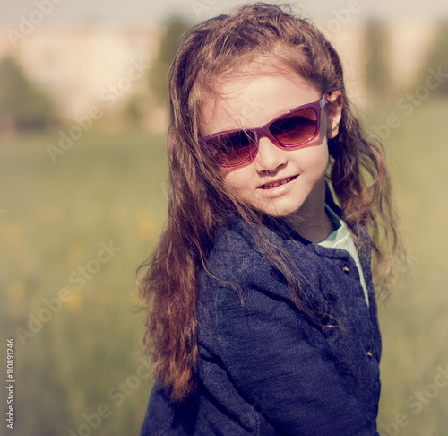 Fashion kid girl posing in blue jacket and sun glasses on spring © nastia1983