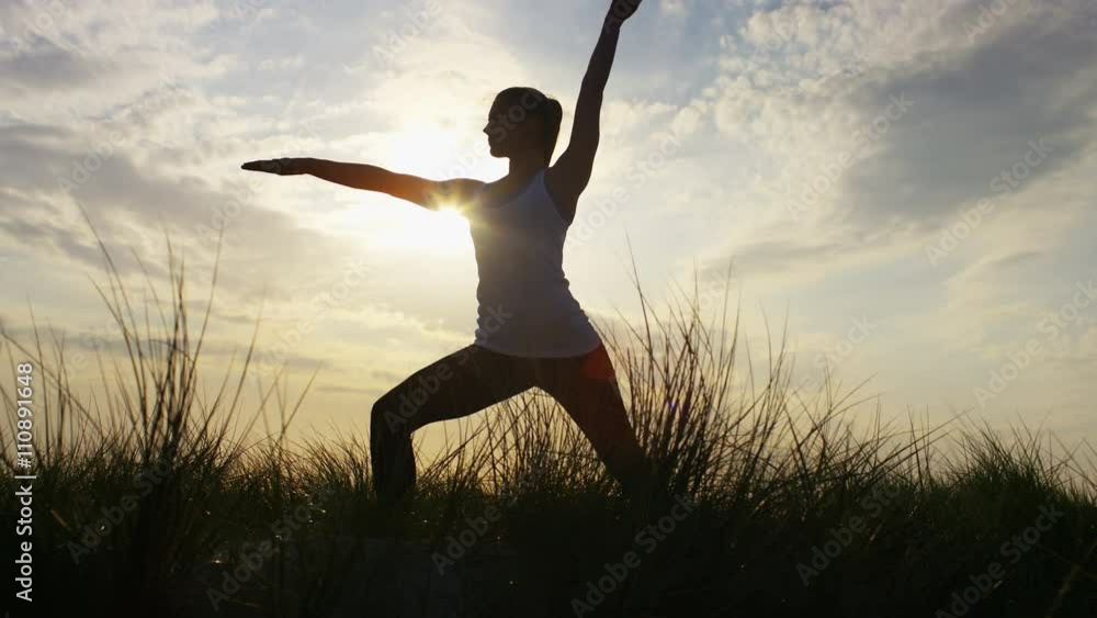 4K Silhouette female doing a warrior yoga pose, in slow motion