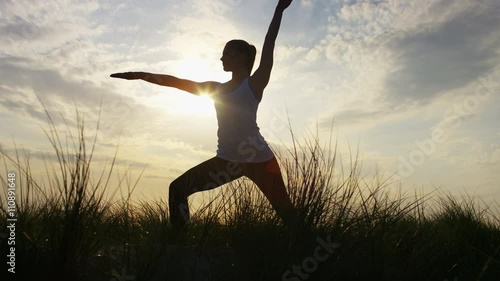 4K Silhouette female doing a warrior yoga pose, in slow motion