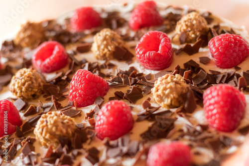 Fotografija Fruchtige Torte mit Himbeeren, Schokoraspeln und Haselnusssplitter, Fokus auf Hi