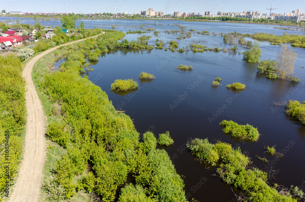 Tyumen, Russia - May 16, 2016: Naberezhnaya Street is protected by a dam from the spread river. On background on other river bank there is the First Zarechny residential district