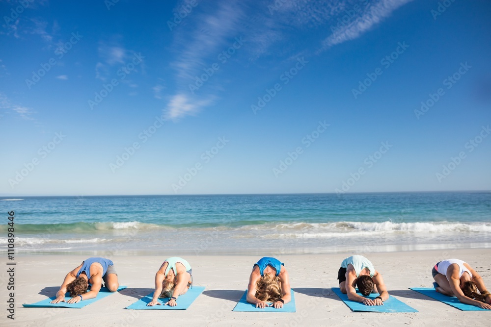 Naklejka premium People doing yoga on the beach