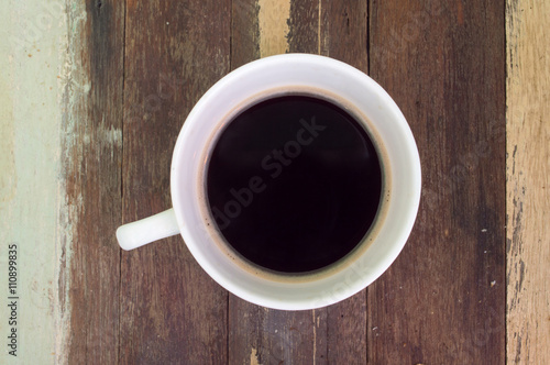 Coffee in white cup on a wooden floor.