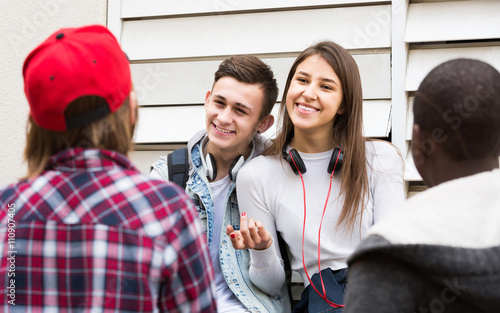 girl and three boys hanging out outdoors and discussing somethin photo