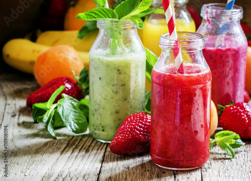 Multi-colored bottles with fresh fruit smoothies with striped st photo