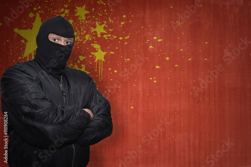 dangerous man in a mask standing near a wall with painted national flag of china