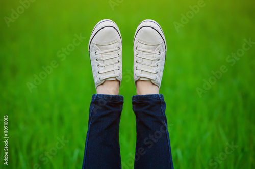 Raised up feet shod in sneakers on a green background.