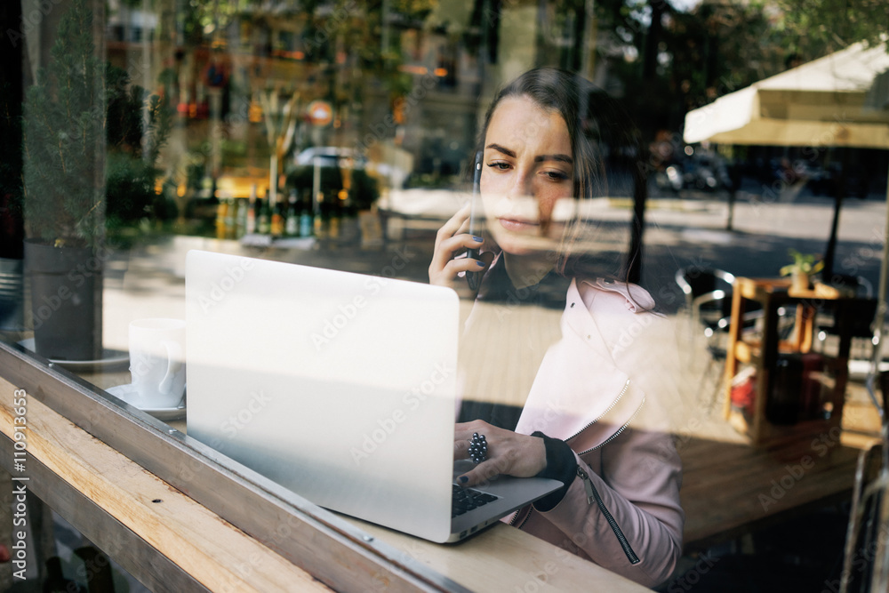 Fototapeta premium attractive Caucasian woman talking on cell telephone during work on portable laptop computer.young modern business woman holding talks on the phone with business partners.