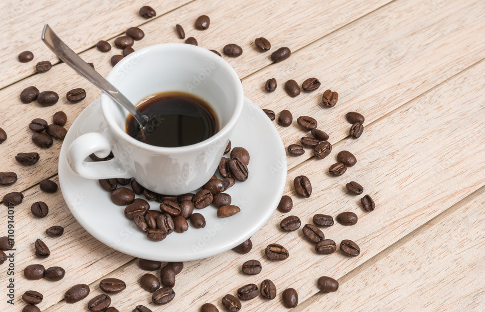 Cup of coffee beans with a spoon and saucer on a white background with the outline of more coffee beans Cup of coffee beans with a spoon and saucer on a white background with the outline of more coffee beans