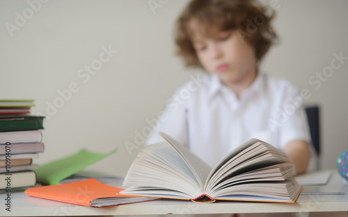 The boy does his homework sitting at a school desk