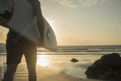 Mature man, walking towards sea, holding surf board photo