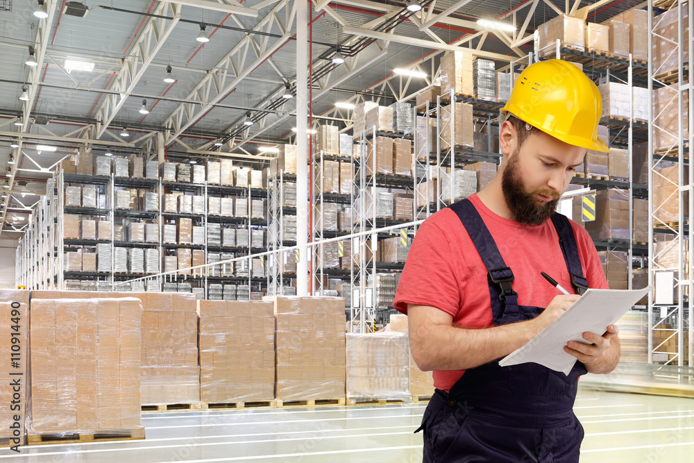 A worker writes documents in a huge distribution warehouse A worker writes documents in a huge distribution warehouse