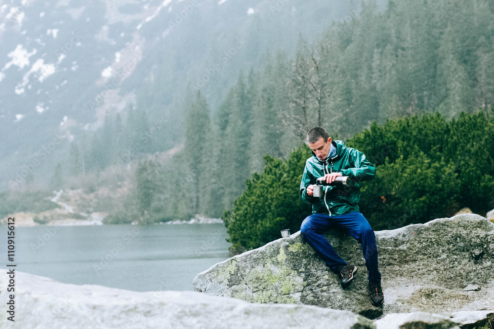 Portrait of young fit male hiker drinking tea on top of the mountain Portrait of young fit male hiker drinking tea on top of the mountain