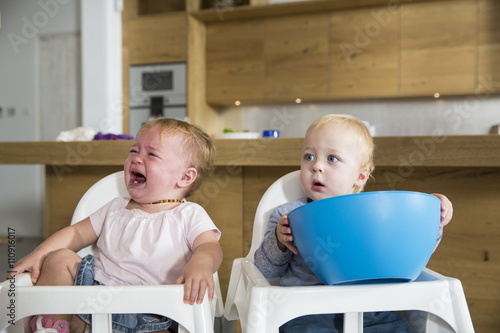 Male and female twin toddlers in high chairs photo